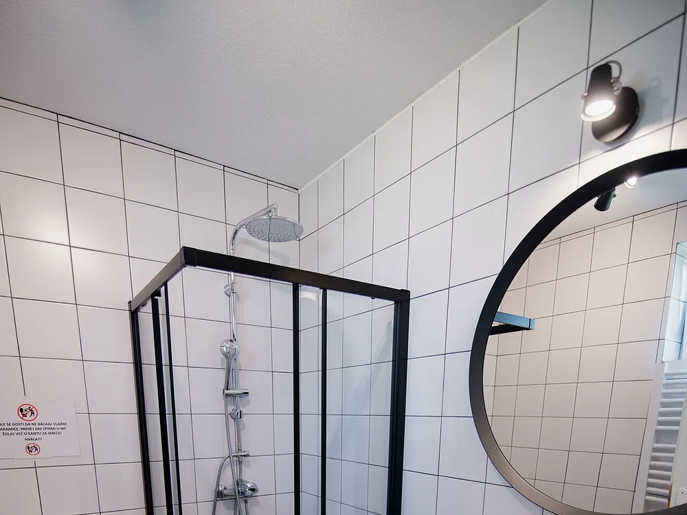 Baño reformado con mampara negra y mueble de madera